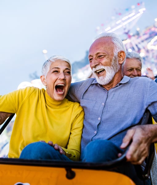 Old man and woman smiling riding a rollercoaster