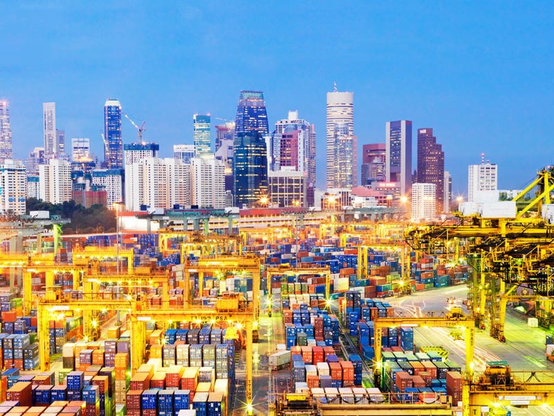 Elevated view of container port at dusk, with Singapore financial district and skyline